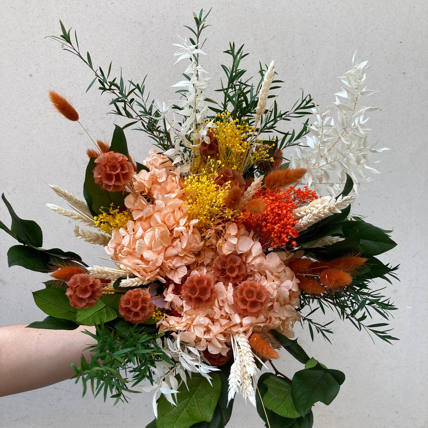 Bouquet en fleurs stabilisées éternelles orange et vert composé de Hortensia, scabieuse, blé, Lepto, Ruscus, Broom, Lagurus, Salal. Vu de face