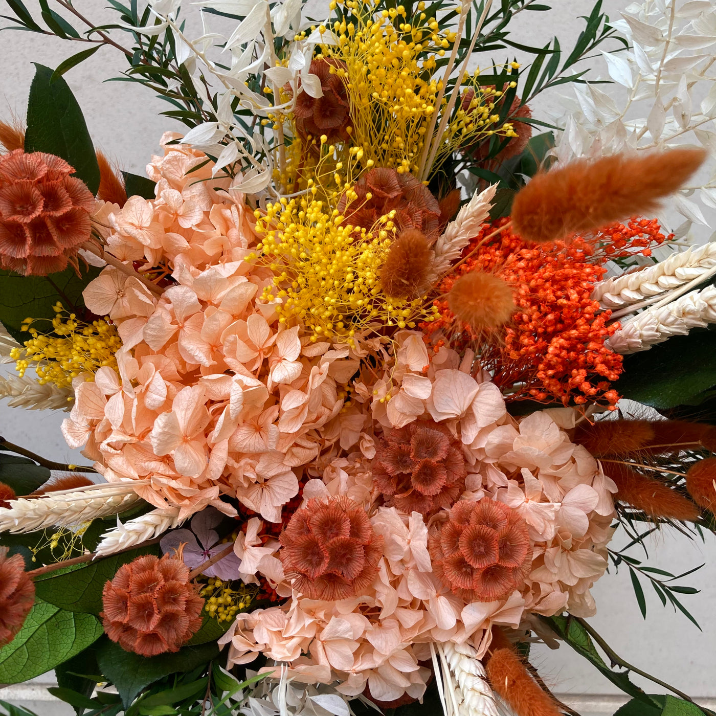 Bouquet en fleurs stabilisées éternelles orange et vert composé de Hortensia, scabieuse, blé, Lepto, Ruscus, Broom, Lagurus, Salal. Vu du haut