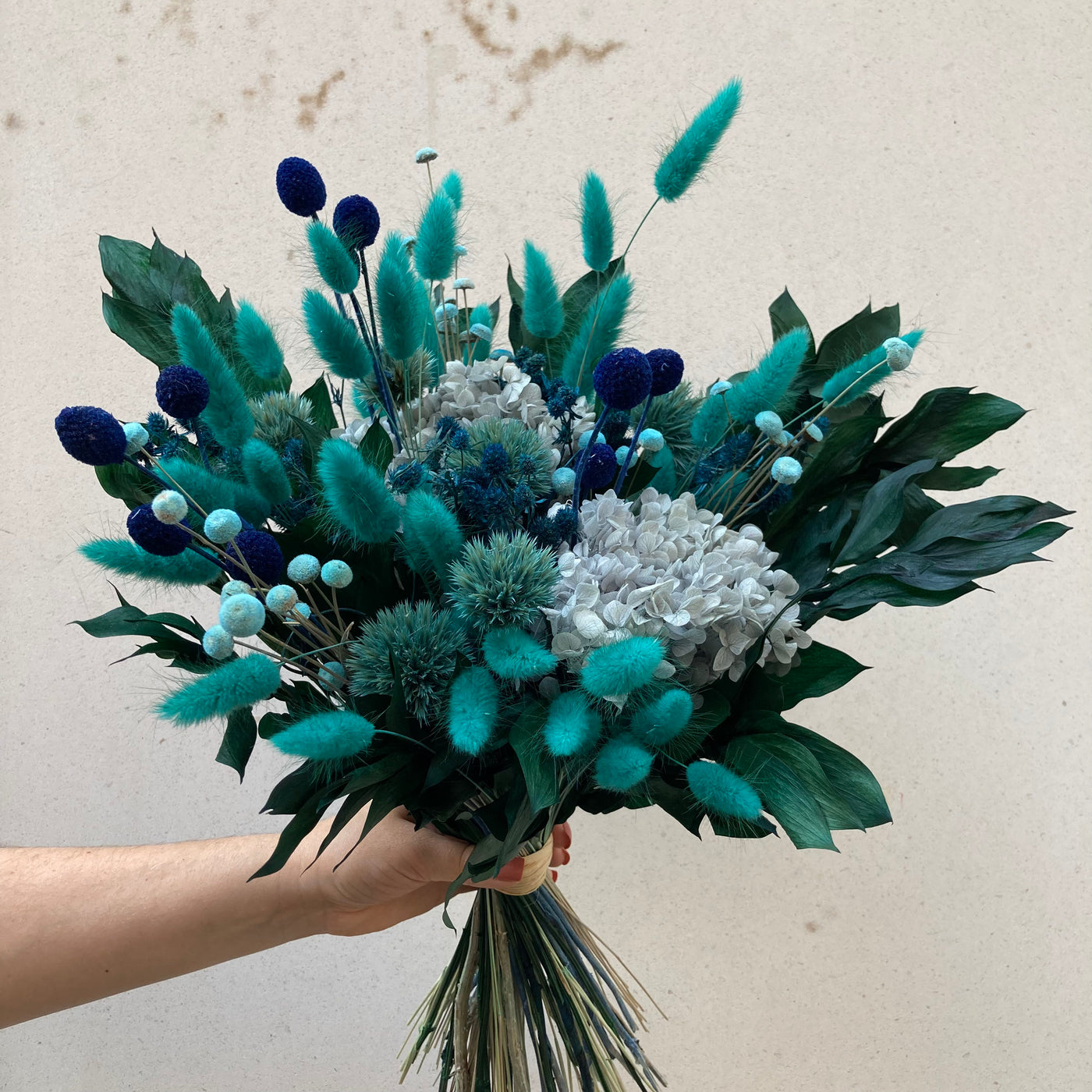 Bouquet en fleurs stabilisées éternelles bleu composé de Lagurus, Hortensia, Ruscus, Chardon, Craspédia, Mini Chardon, Botao. Vu de côté