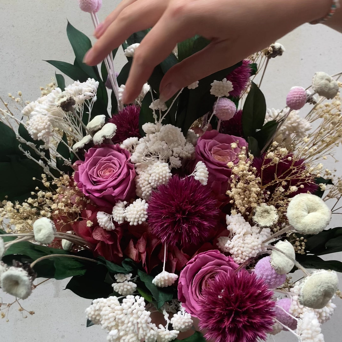 Bouquet de fleurs stabilisées éternelles rose et blanc composé de Rose, Chardon, Achillée, Craspédia, Ruscus, Gypsophile, Pali Pala, Hortensia. En mouvement