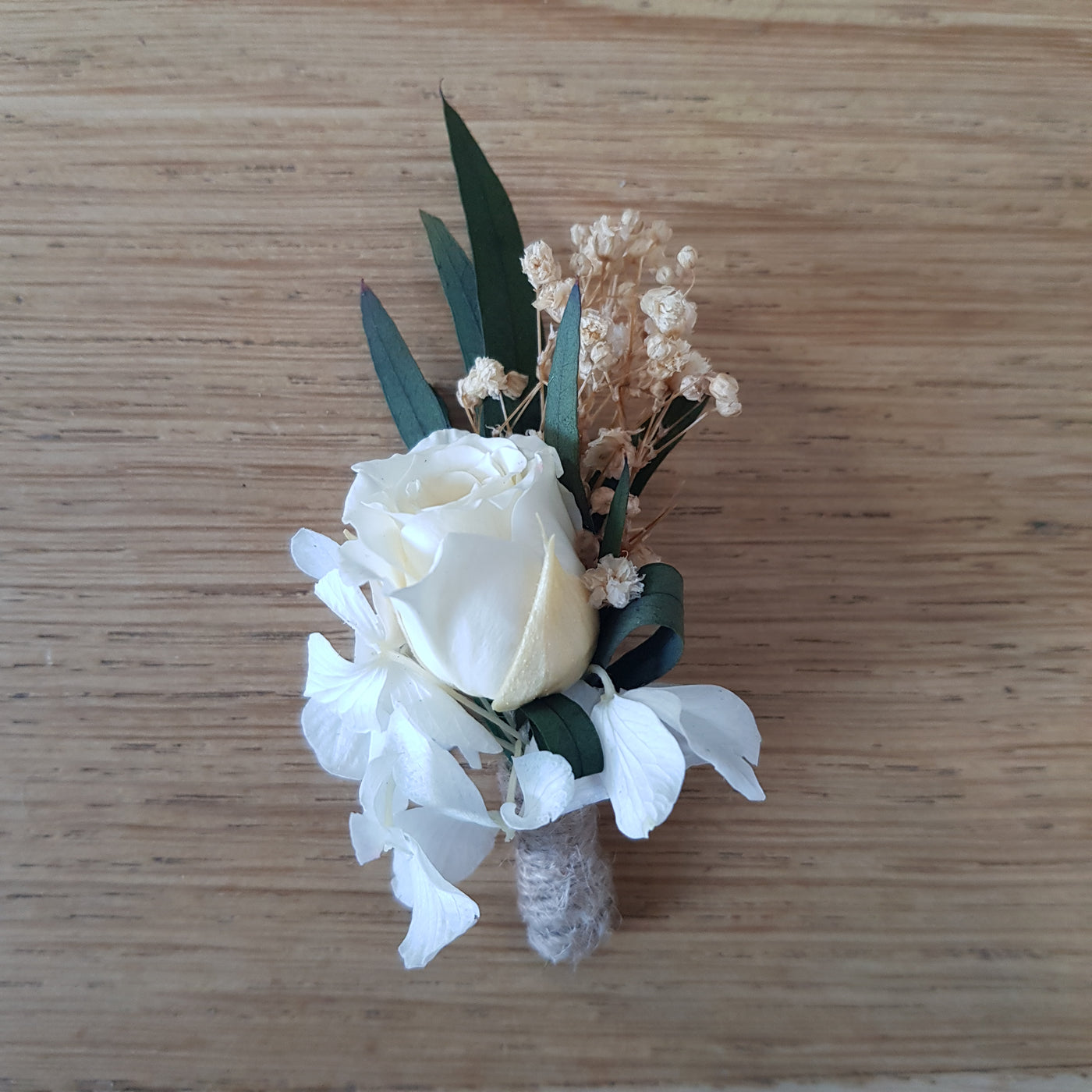 Boutonnière en fleurs stabilisées éternelles blanche composé de Rose, Hortensia, Gypsophile & Nicoly. Vue de face