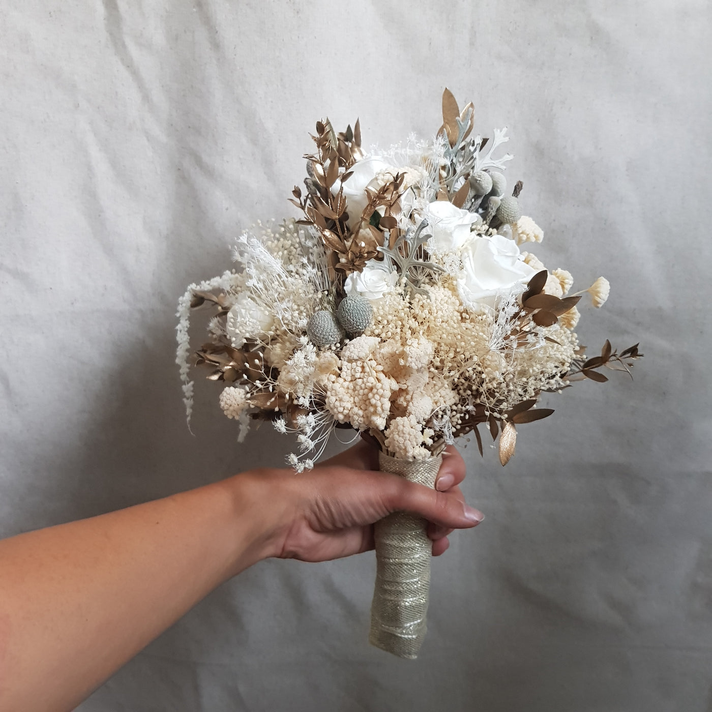 Bouquet de mariée en fleurs stabilisées éternelles blanc composé de Rose, Mini Gypsophile, Achilée, Cineraria, Ruscus, Brunia. Vu du côté droit 