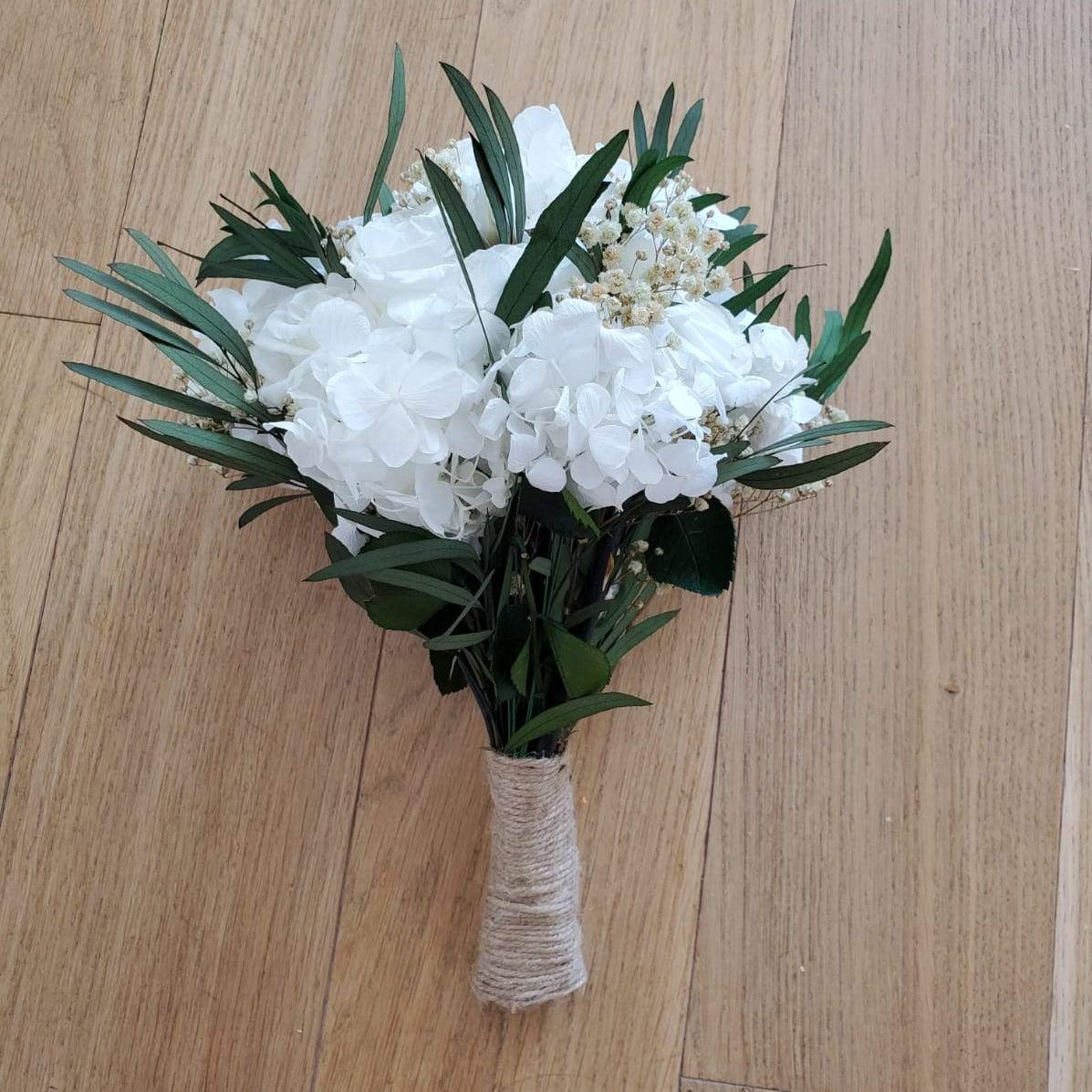 Bouquet de mariée en fleurs stabilisées éternelles blanc composé de Roses, Hortensia, Gypsophile & eucalyptus Nicoli. Vu du côté gauche. 